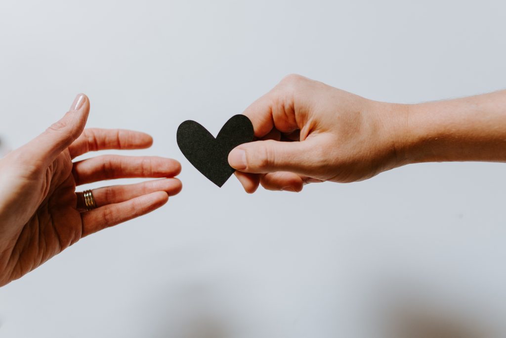 Someone is holding a heart and giving it to someone else to support their mental health.